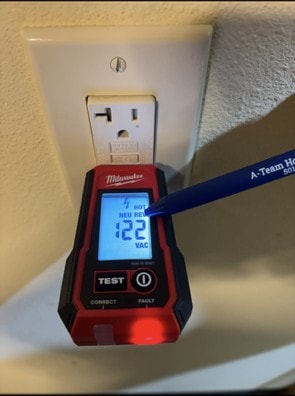 Electrical outlet tester in a bathroom receptacle displaying a HOT NEU REV reversed-polarity fault.