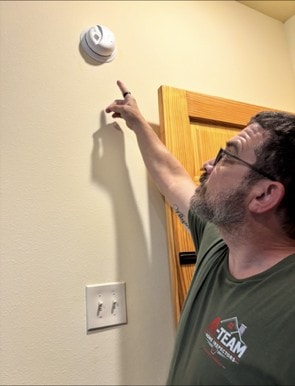 Smoke alarm mounted on the hallway ceiling outside a bedroom door.