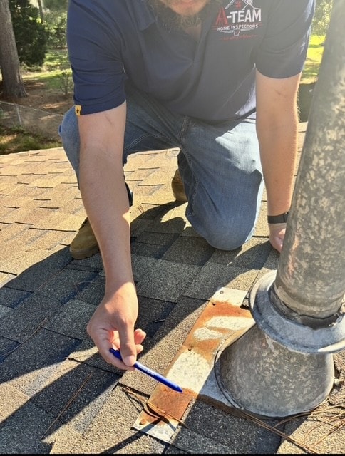 Metal plumbing vent boot on an asphalt shingle roof with heavy rust along the lower flange and missing fasteners.