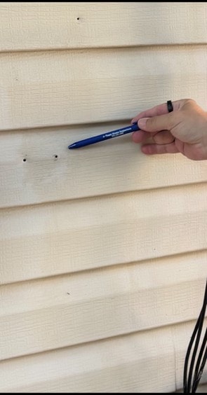 Vinyl siding panel with several open, unsealed screw holes left behind after equipment was removed.
